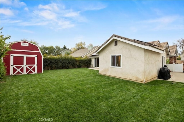 view of yard with fence, an outdoor structure, a patio, and a storage shed
