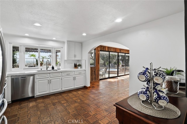 27955 Gallina, Mission Viejo, CA 92692 - kitchen featuring stainless steel dishwasher, arched walkways, light countertops, a textured ceiling, and white cabinetry