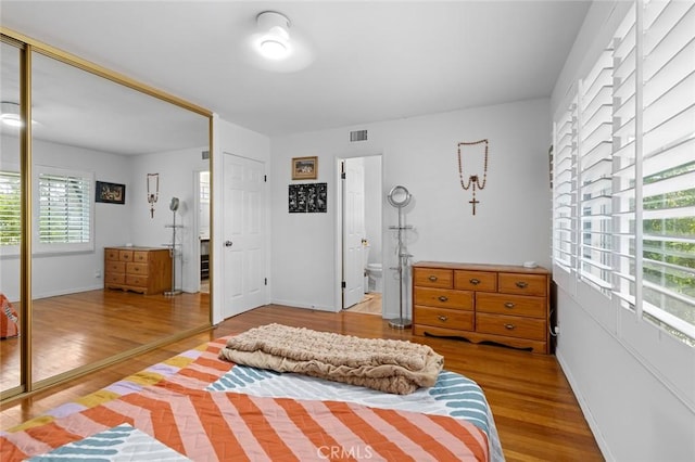 bedroom featuring baseboards, wood finished floors, a closet, and visible vents