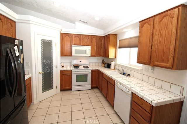 17255 Donert St, Hesperia, CA 92345 - kitchen with white appliances, visible vents, brown cabinetry, and lofted ceiling