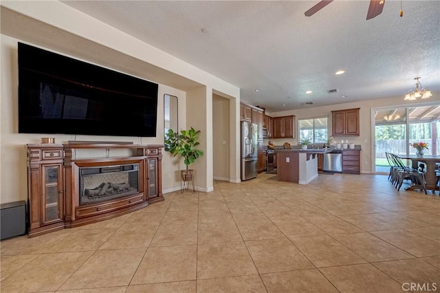 living area featuring light tile patterned floors, a textured ceiling, baseboards, recessed lighting, and ceiling fan with notable chandelier