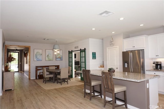 34539 Velvetleaf St, Winchester, CA 92596 - kitchen featuring stainless steel refrigerator with ice dispenser, a barn door, white cabinetry, light wood finished floors, and recessed lighting