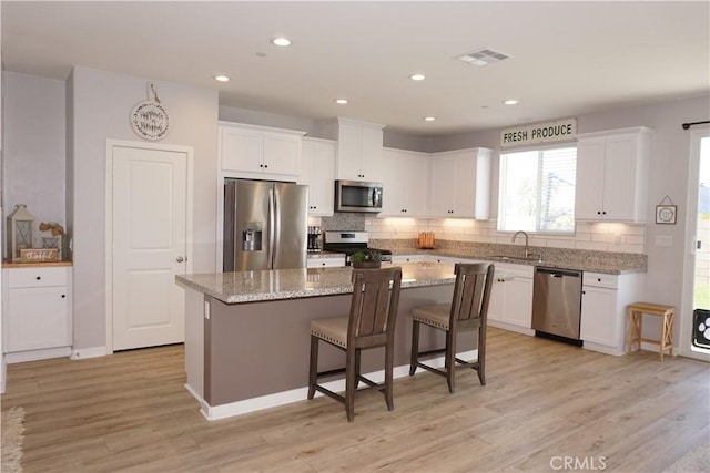 34539 Velvetleaf St, Winchester, CA 92596 - kitchen with stainless steel appliances, a center island, a sink, white cabinets, and decorative backsplash