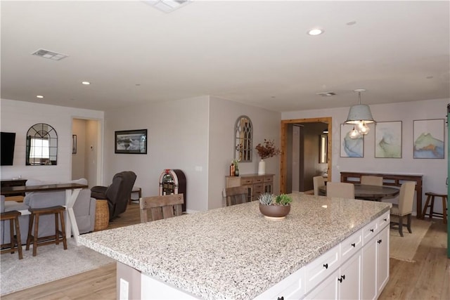 34539 Velvetleaf St, Winchester, CA 92596 - kitchen featuring white cabinetry, open floor plan, light wood-style floors, light stone counters, and a center island