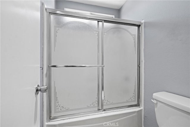full bath with an enclosed shower, toilet, and a textured wall