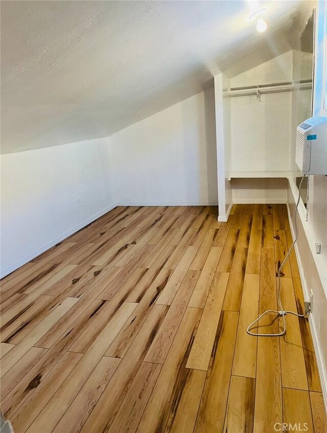 additional living space with baseboards and wood finished floors