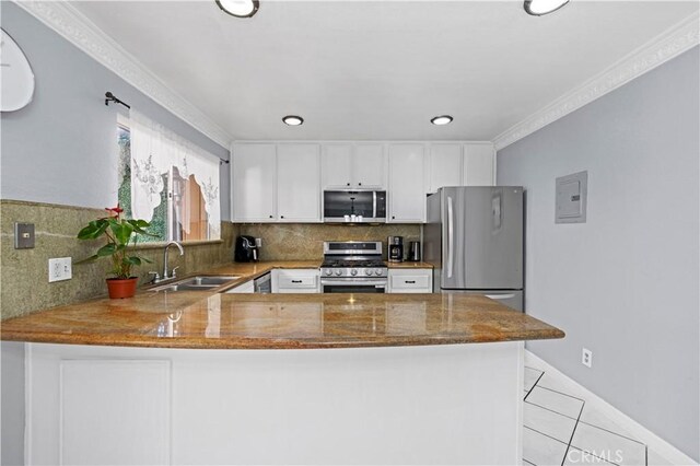 kitchen featuring a sink, white cabinetry, a peninsula, stainless steel appliances, and tasteful backsplash