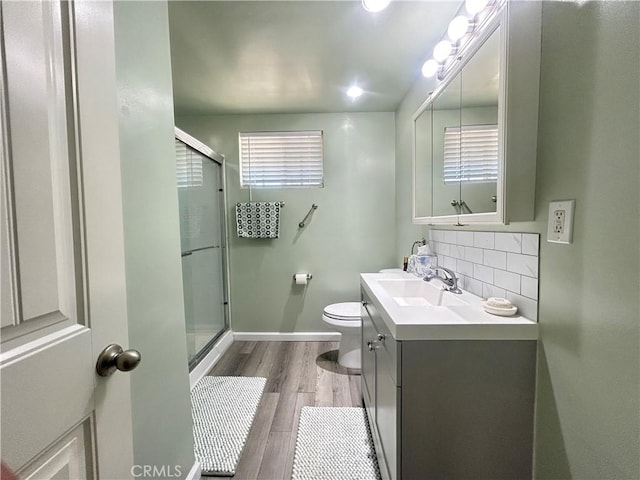 bathroom featuring toilet, wood finished floors, a shower stall, and tasteful backsplash