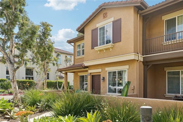 townhome / multi-family property with a tiled roof and stucco siding