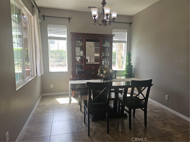 dining space with visible vents, baseboards, a notable chandelier, a barn door, and tile patterned floors
