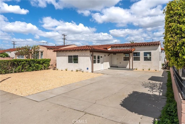 view of front of house featuring a tile roof, stucco siding, and fence