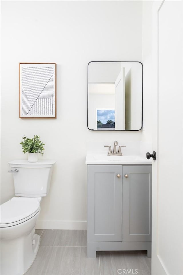 bathroom with baseboards, toilet, and vanity
