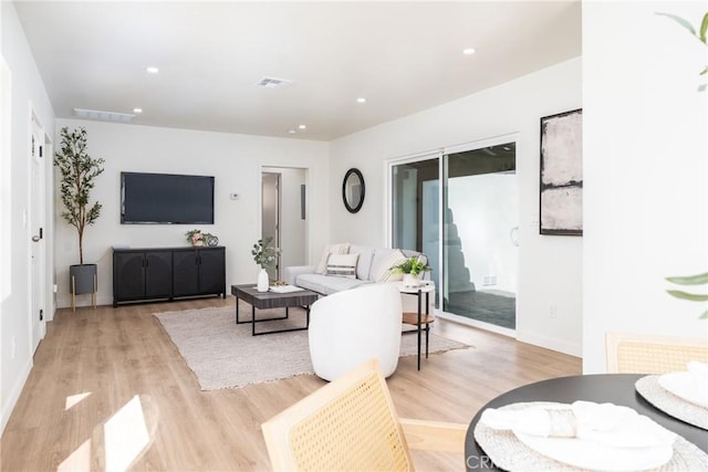 living area featuring baseboards, visible vents, light wood-style flooring, and recessed lighting