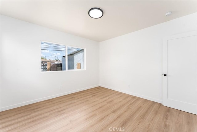 empty room with baseboards and light wood-type flooring