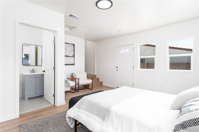 bedroom with a sink, baseboards, light wood-style flooring, and visible vents