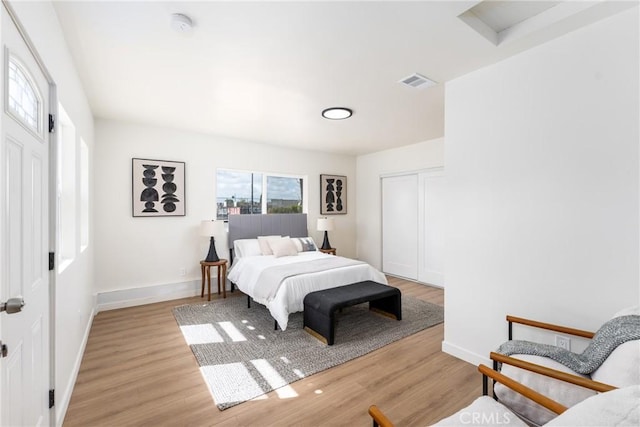 bedroom featuring baseboards, a closet, visible vents, and light wood-style floors