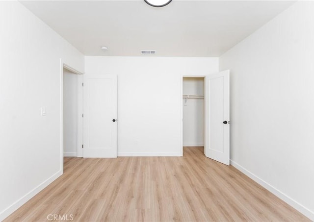 unfurnished bedroom featuring visible vents, baseboards, a closet, and wood finished floors