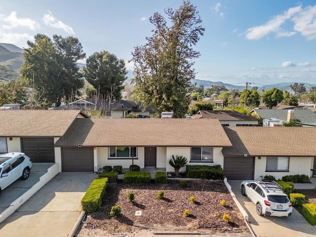 single story home with driveway, stucco siding, an attached garage, and a mountain view