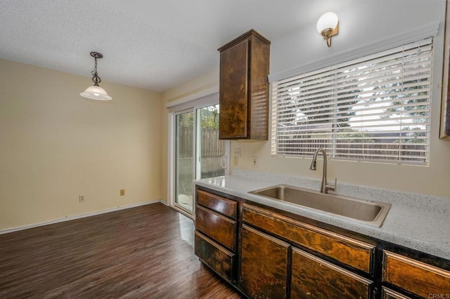 kitchen featuring dark wood-style flooring, baseboards, a sink, pendant lighting, and dark brown cabinets