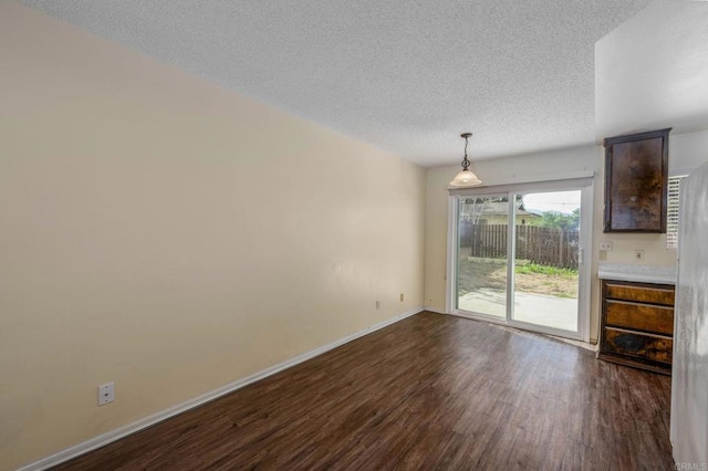 unfurnished dining area with dark wood finished floors, baseboards, and a textured ceiling