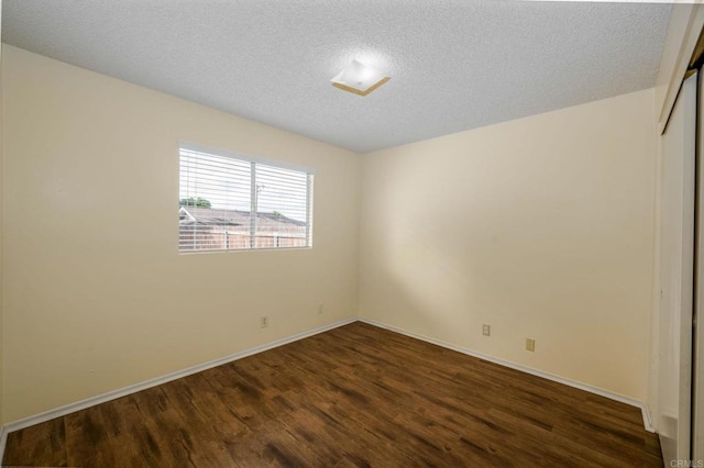 spare room with dark wood-style flooring, baseboards, and a textured ceiling