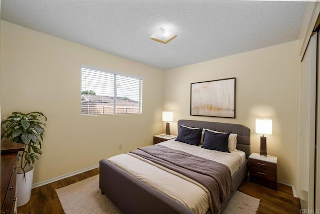 bedroom featuring baseboards, a textured ceiling, wood finished floors, and a closet