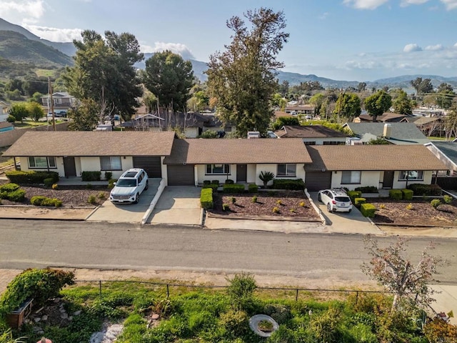 view of front facade with an attached garage, a mountain view, concrete driveway, and a residential view