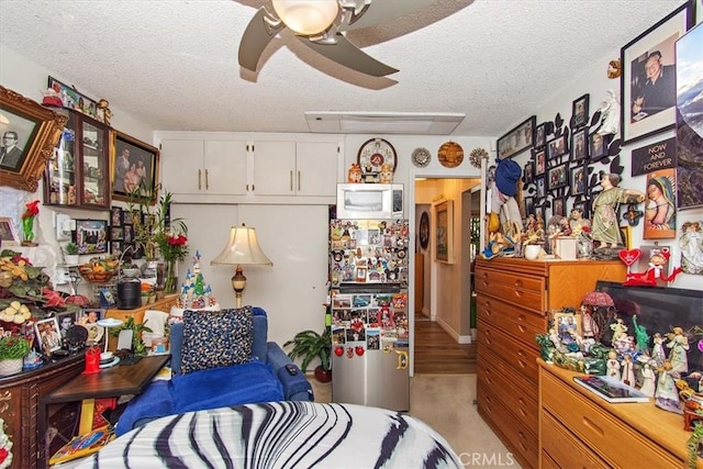 bedroom with freestanding refrigerator, a textured ceiling, and ceiling fan