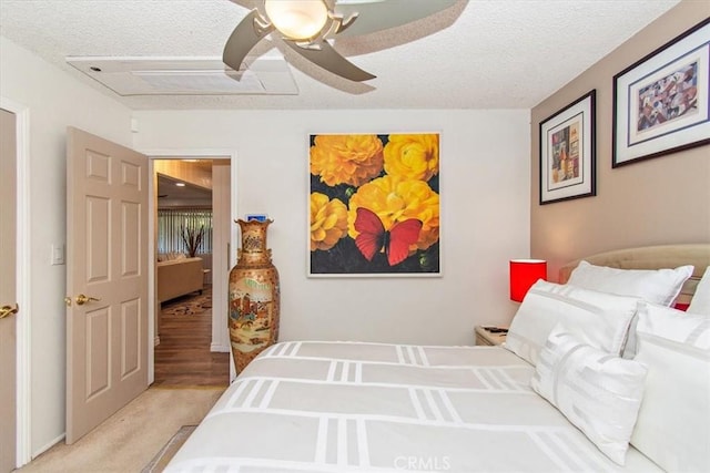 bedroom with a textured ceiling, a ceiling fan, and light carpet