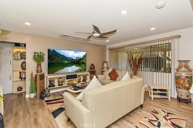living room featuring wood finished floors, a textured ceiling, and a ceiling fan