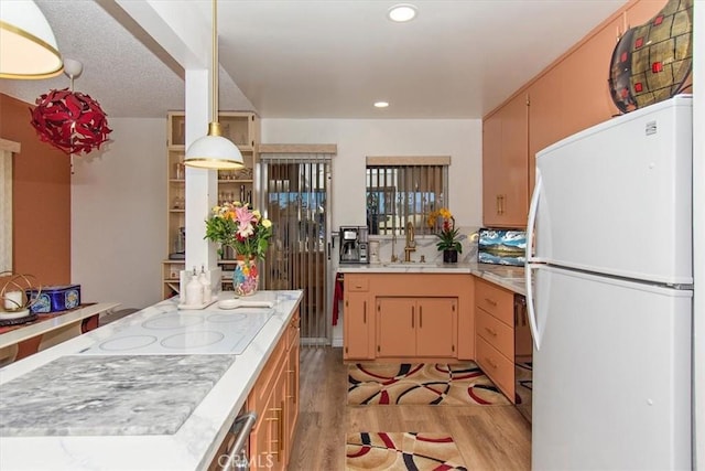 kitchen with recessed lighting, light countertops, a sink, white appliances, and light wood-type flooring