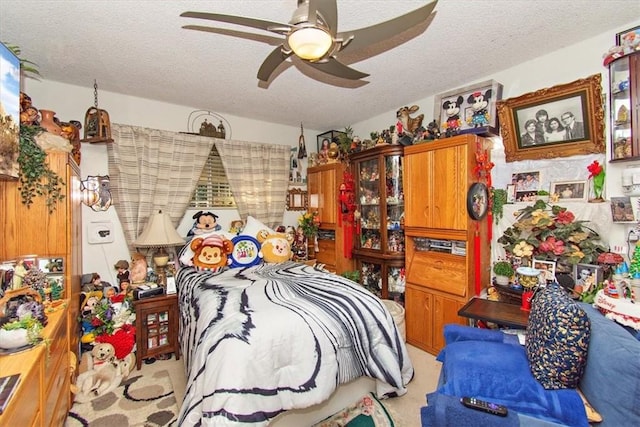 bedroom featuring a textured ceiling, light colored carpet, and ceiling fan