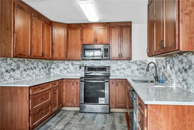 kitchen with light countertops, a sink, brown cabinetry, and appliances with stainless steel finishes