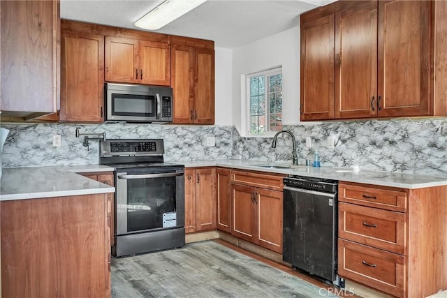 kitchen featuring light countertops, a sink, appliances with stainless steel finishes, and brown cabinets