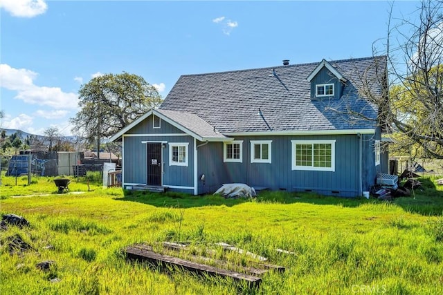rear view of property with crawl space, a lawn, board and batten siding, and roof with shingles
