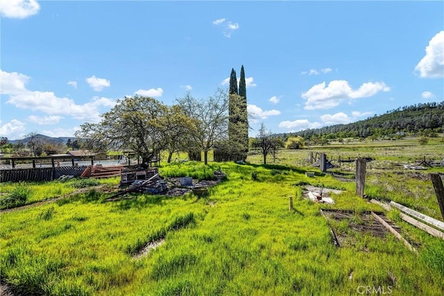 view of yard featuring fence, a rural view, and a mountain view