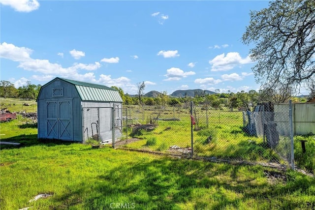 view of yard featuring a storage unit, an outdoor structure, fence, and a mountain view