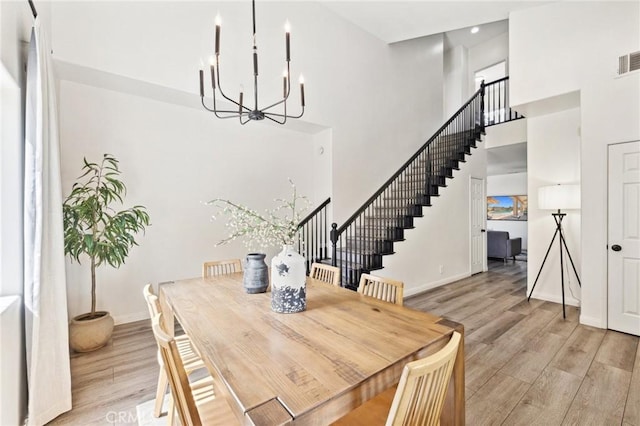 43475 Brahea Ct, Indio, CA 92201 - dining area featuring a high ceiling, a chandelier, light wood-style floors, baseboards, and stairs