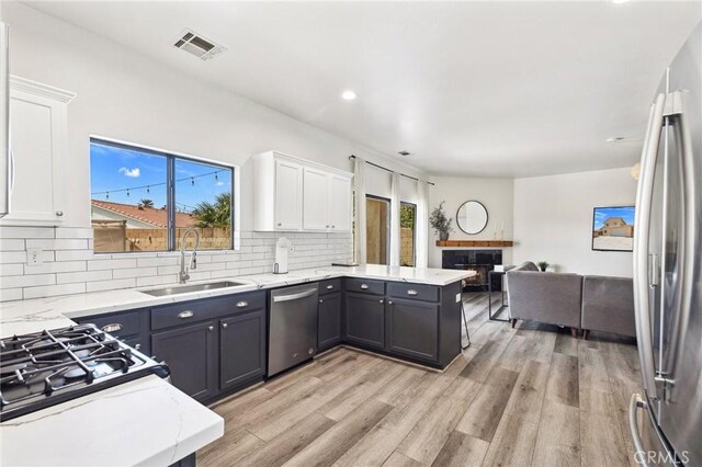 43475 Brahea Ct, Indio, CA 92201 - kitchen featuring a sink, appliances with stainless steel finishes, white cabinets, a peninsula, and backsplash
