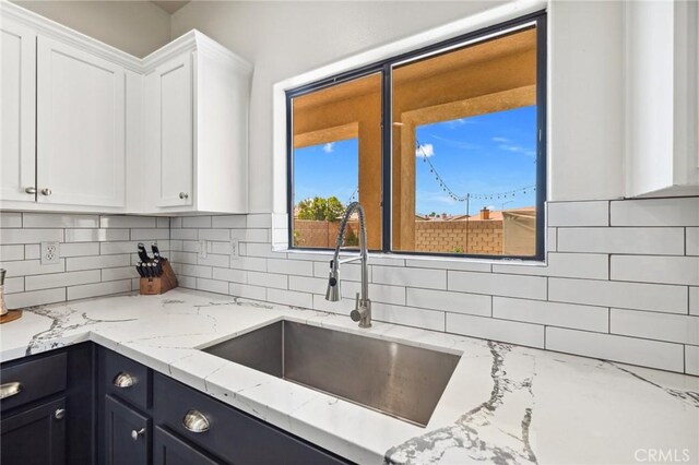 43475 Brahea Ct, Indio, CA 92201 - kitchen with white cabinetry, tasteful backsplash, a sink, and light stone countertops