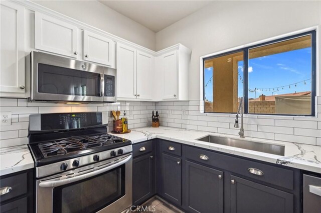 43475 Brahea Ct, Indio, CA 92201 - kitchen with appliances with stainless steel finishes, a sink, white cabinets, backsplash, and light stone countertops