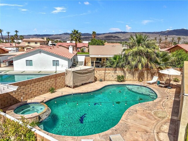 43475 Brahea Ct, Indio, CA 92201 - view of swimming pool with a mountain view, a fenced backyard, a pool with connected hot tub, a patio, and a residential view