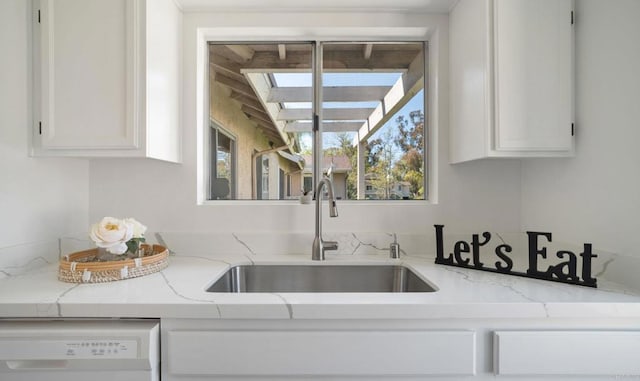kitchen featuring dishwasher, white cabinetry, light stone countertops, and a sink