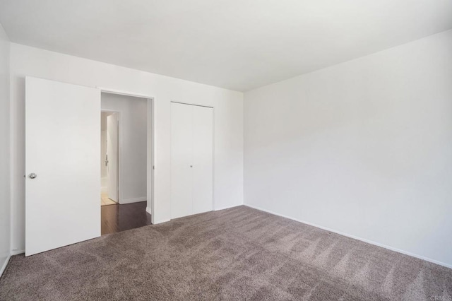 unfurnished bedroom with carpet floors, a closet, and baseboards
