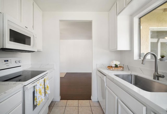 kitchen with light stone counters, white cabinetry, a sink, and white appliances