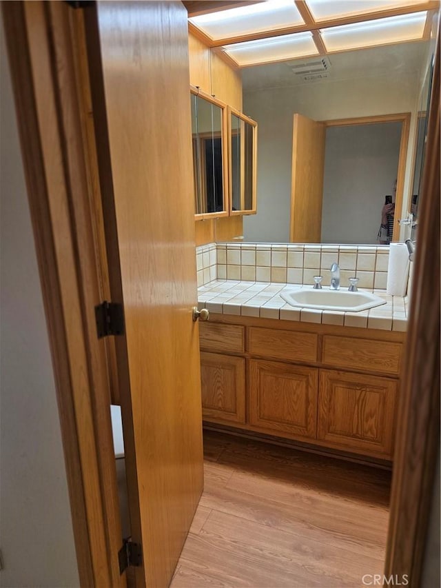 bathroom featuring vanity, decorative backsplash, and wood finished floors