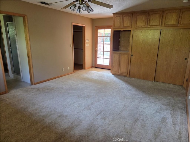 unfurnished bedroom featuring visible vents, light carpet, baseboards, ceiling fan, and ensuite bath