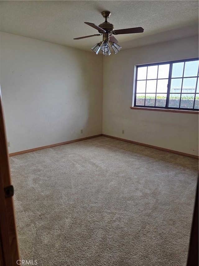 unfurnished room featuring a ceiling fan, a textured ceiling, baseboards, and carpet