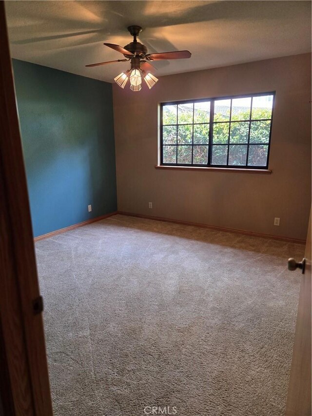 carpeted spare room with baseboards and a ceiling fan