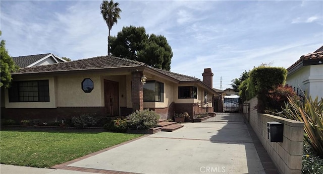 bungalow-style home featuring a chimney, a gate, brick siding, a front lawn, and stucco siding
